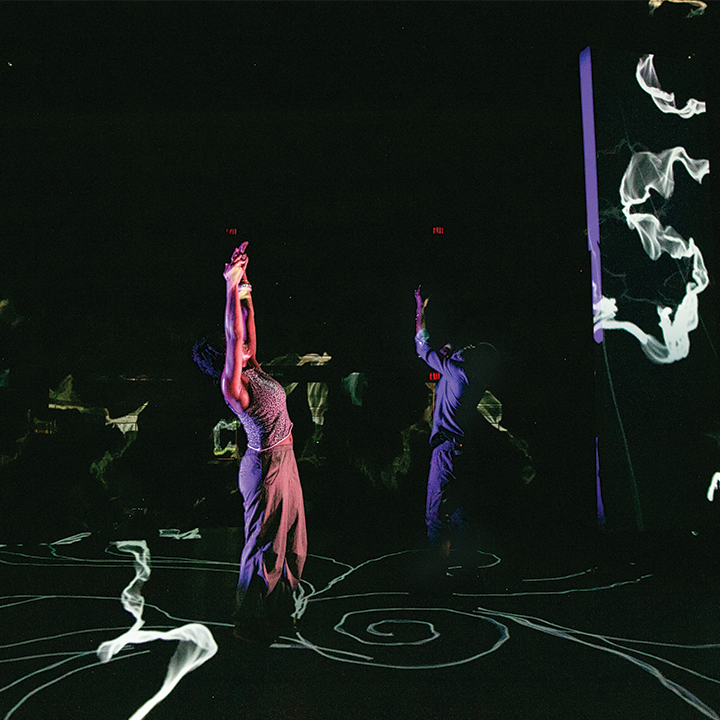 Two dancers performing in a dark room